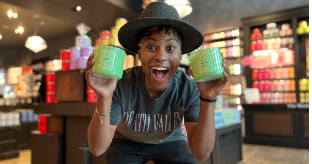 woman excitedly holding up Bath & Body Works 3-wick candles in both of her hands