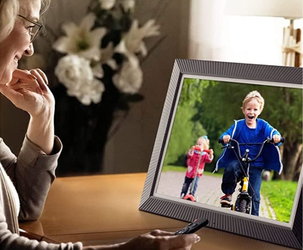 Woman using a large format Benibela digital photo frame with a remote