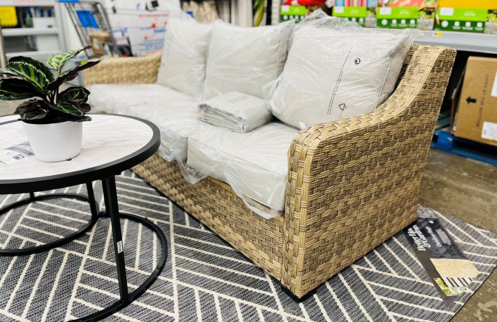 Wicker patio set with a metal table in front of it and a plant on the table