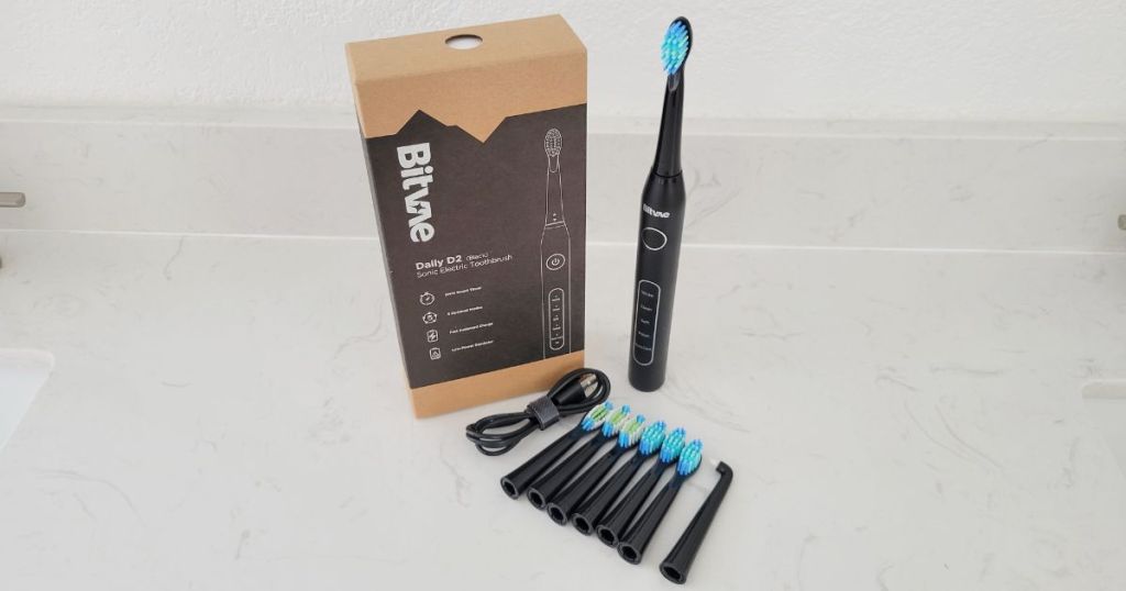 Bitvae electric toothbrush with blue bristles, 7 brush heads, USB cable and Bitvae packaging on counter