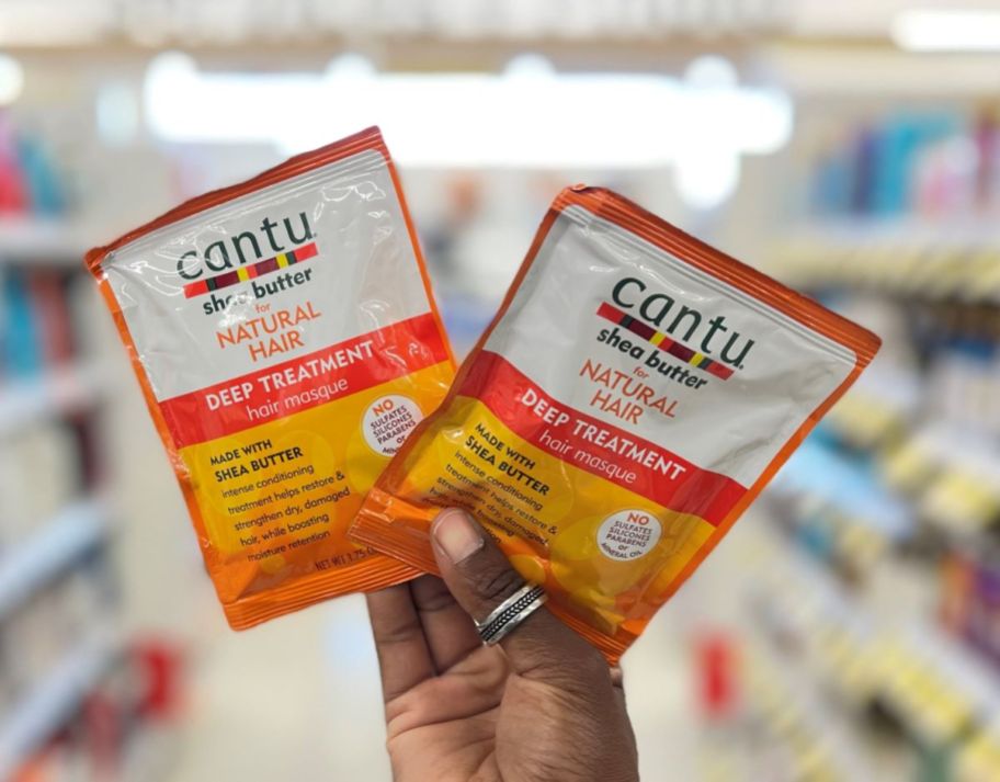 Hand holding two Cantu hair mask packets