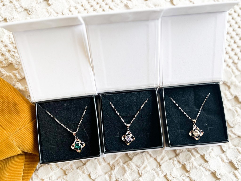 three birthstone necklaces in jewelry boxes