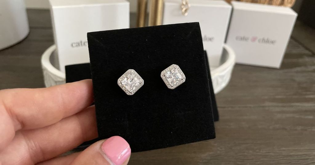 hand holding sparkly square earrings