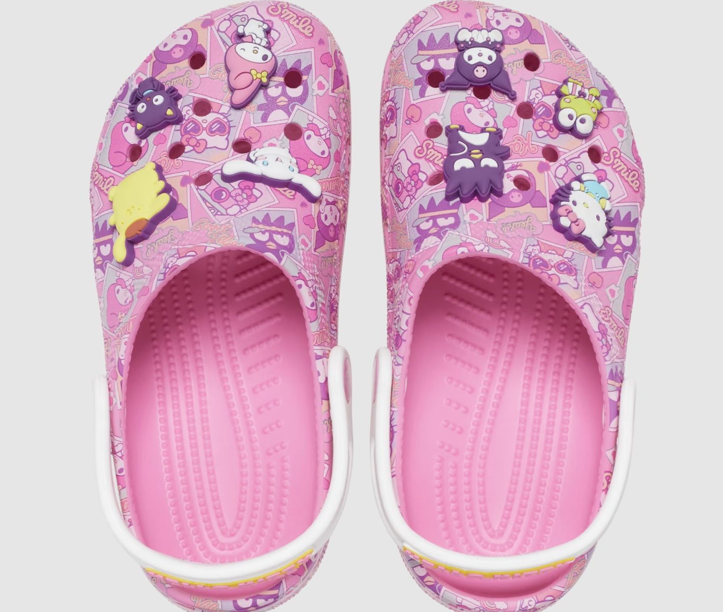 A pair of pink Crocs with Hello Kitty designs and charms on them