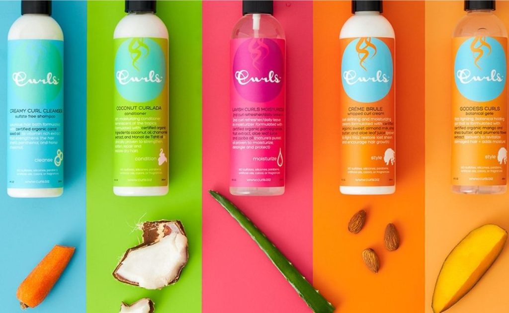 Curls haircare bundle set with with each product next to the main natural ingredient like carrot, coconut, aloe, almonds and mango.