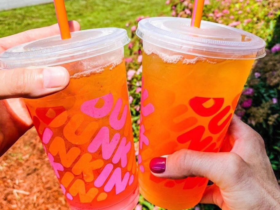Two hands holding Dunkin Refresher drinks