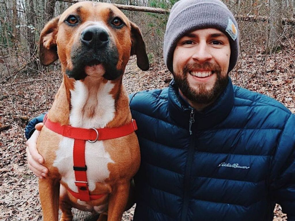 A Man wearing an eddie bauer jacket with his dog next to him