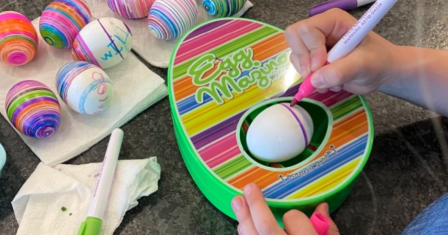 young child coloring eggs with egg mazing kit