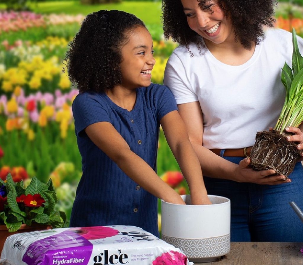 Mom and daughter repotting a plan next to a bag of Glee potting mix