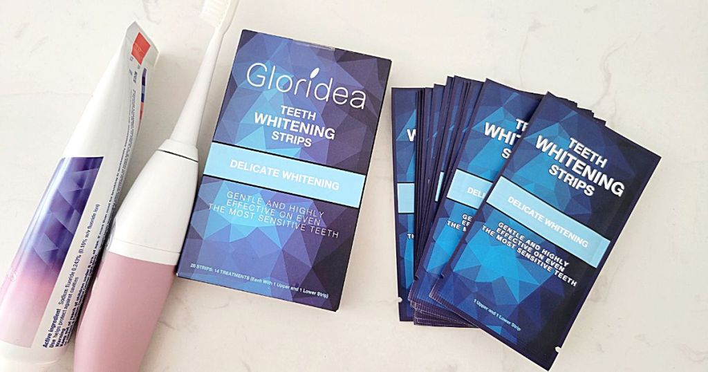 Gloridea Teeth Whitening Strips packages next to toothpaste and toothbrush