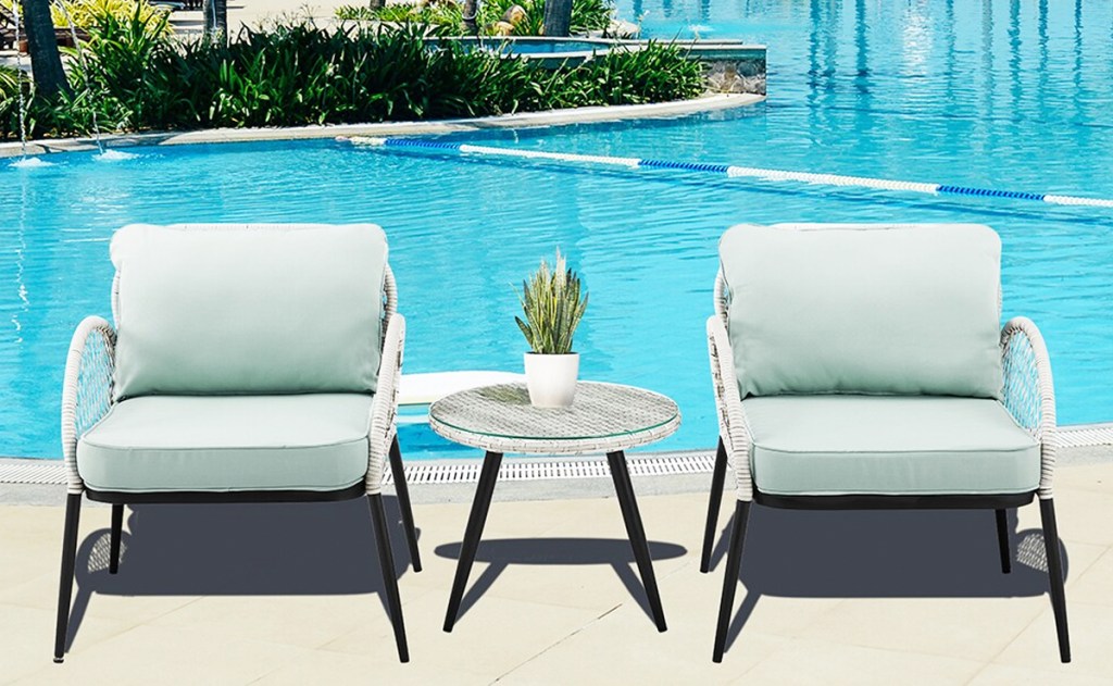 two wicker chairs with cushions and matching table near pool