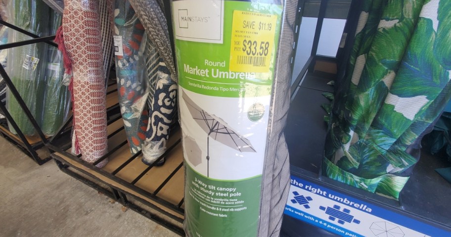 tan patio umbrella in packaging in store with more umbrellas behind it