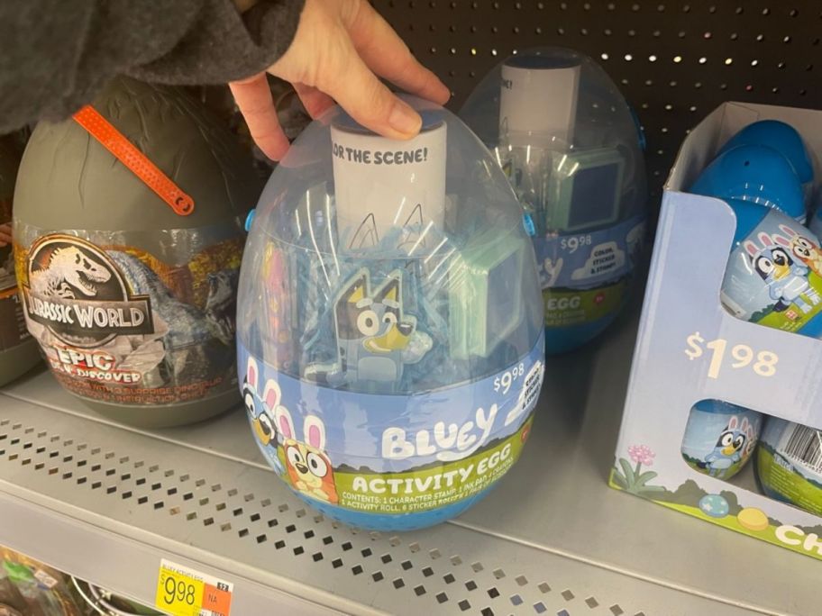 hand reaching for a large Disney Bluey Deluxe Activity Egg on shelf in store