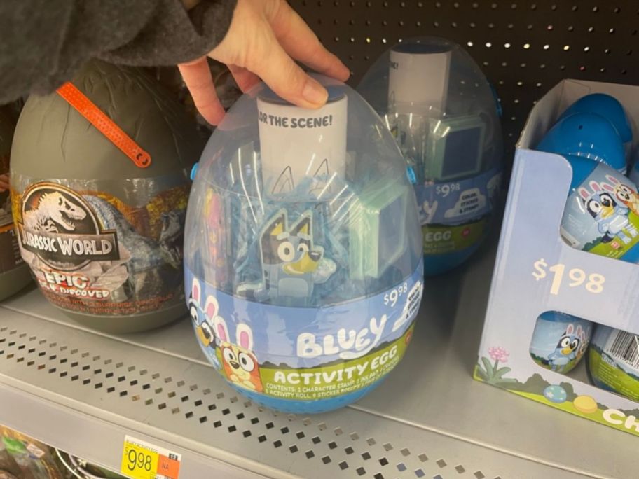 hand reaching for a large Disney Bluey Deluxe Activity Egg on shelf in store