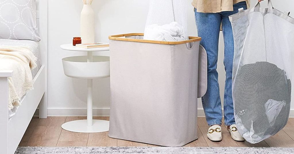 light gray laundry hamper with bamboo lid base opened and person taking removable bag out