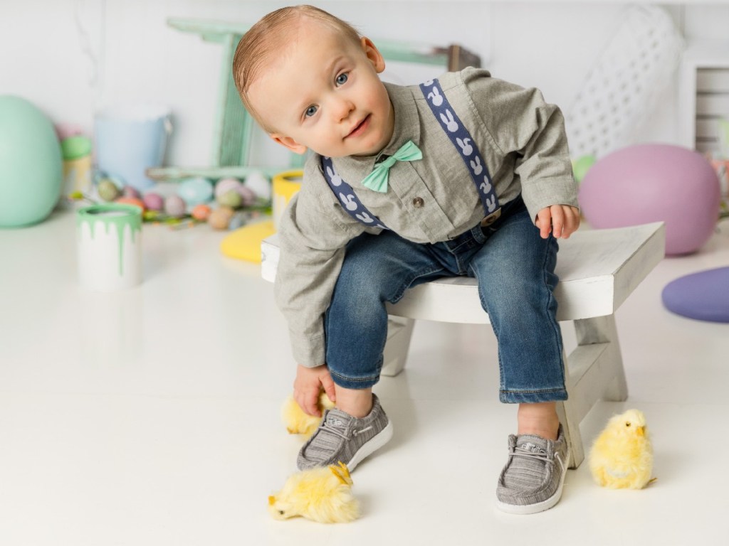 toddler boy playing with chicks wearing Hey Dudes toddler shoes