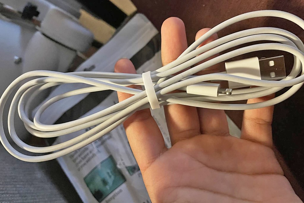 hand holding a white charging cable