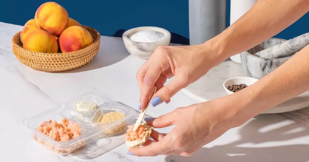 woman assembling ingredients from a Honey Smoked Fish Co. Salmon Stackers kit