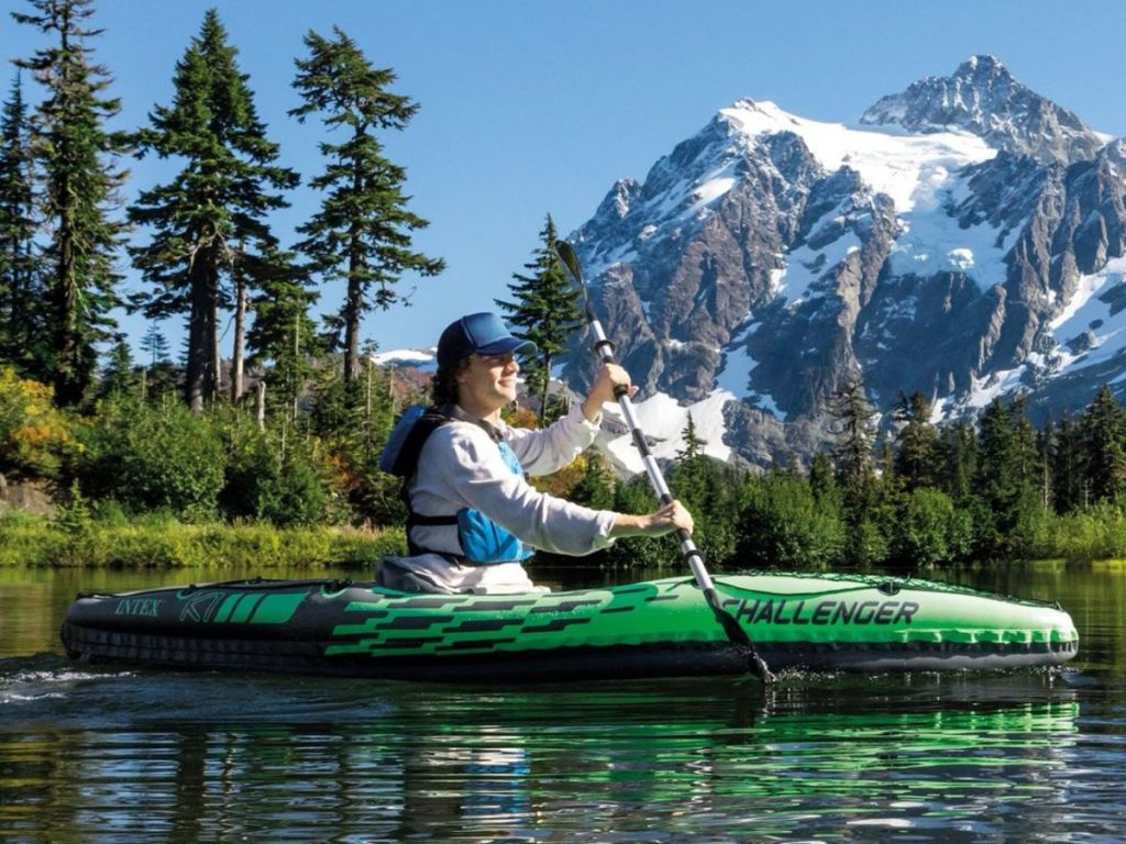 Person in a kayak on the water with a mountain and trees in the background