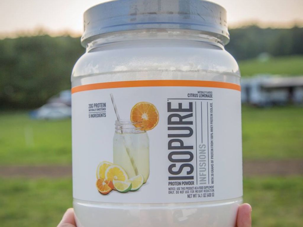 hand holding a large container of Isopure Protein Powder