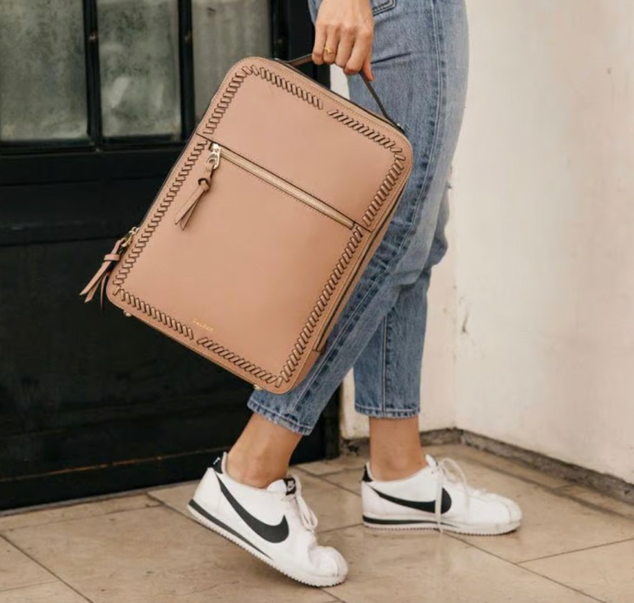 woman holding camel leather backpack