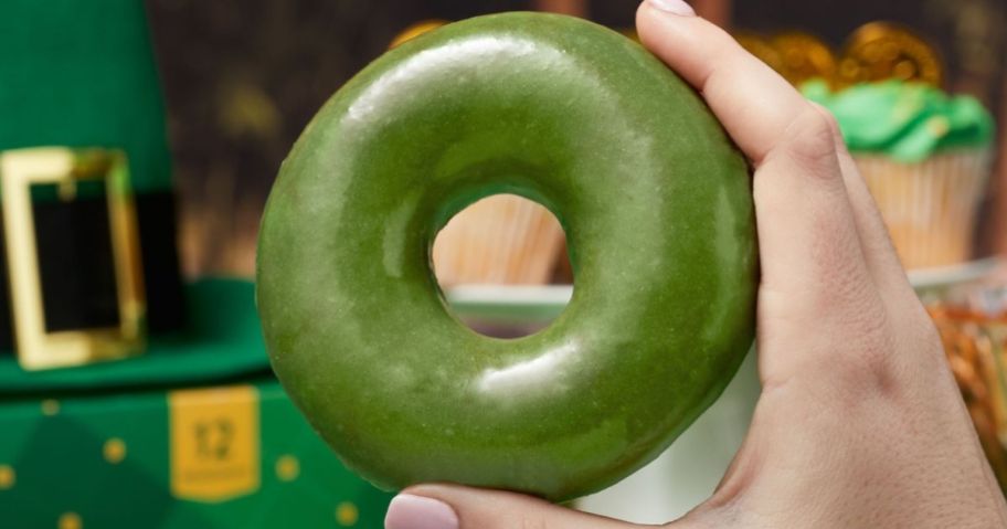 hand holding a green glazed krispy kreme doughnut