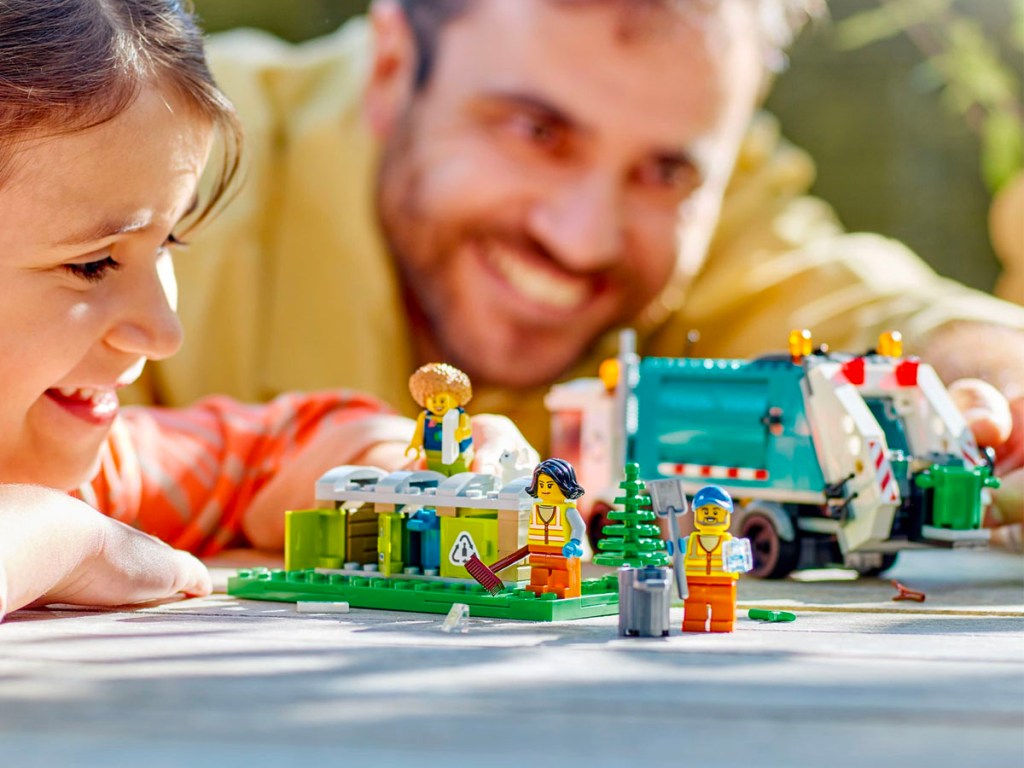 child and man playing with lego recycling set