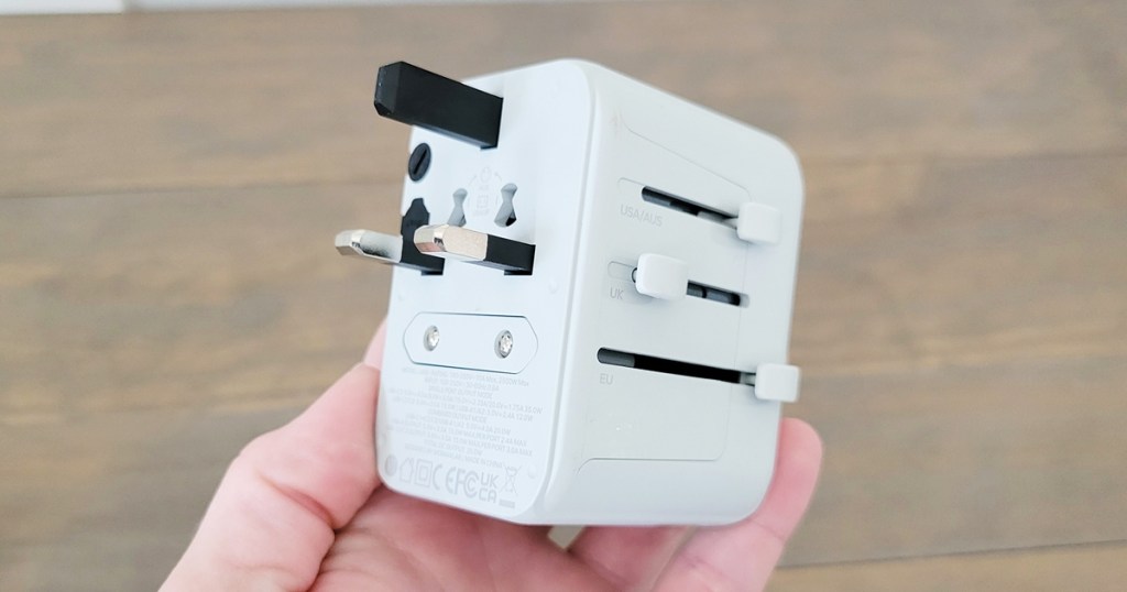 hand holding a white universal travel adapter