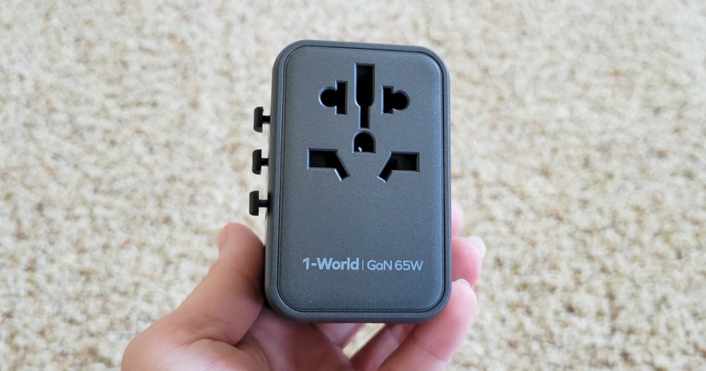 hand holding a black universal travel adapter