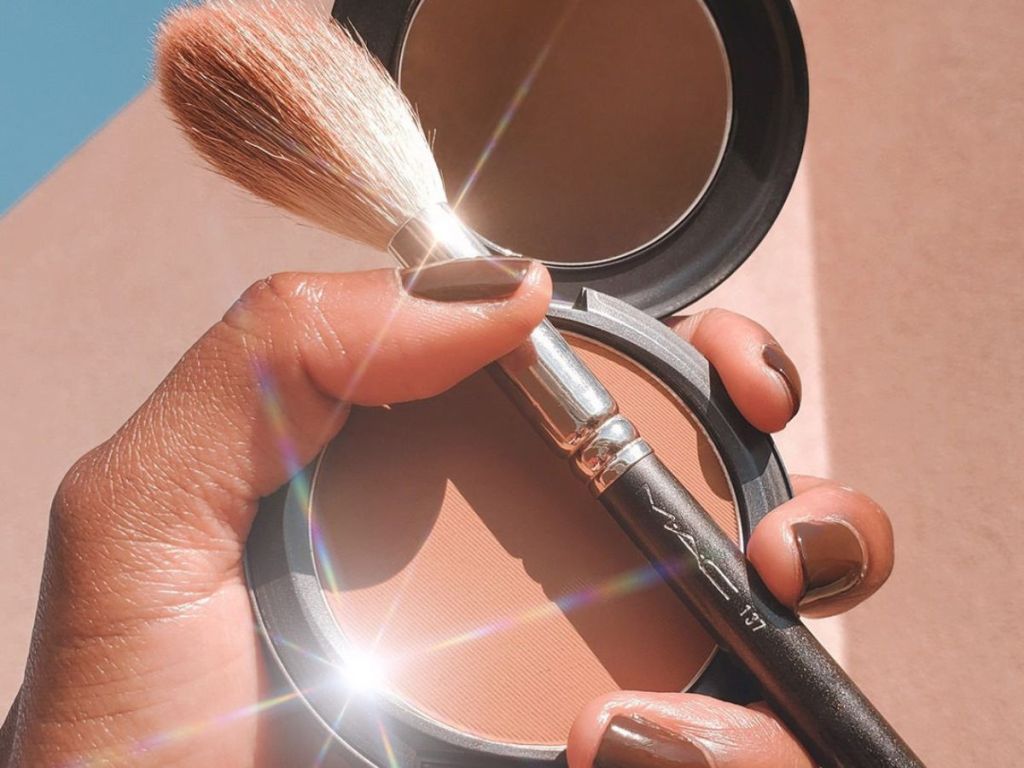 hand holding up an open Mac Studio Fix Powder Foundation compact with a mac makeup brush