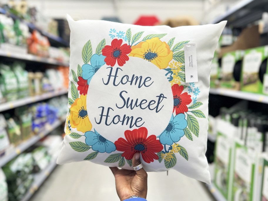 hand holding a floral print throw pillow that says "home sweet home"