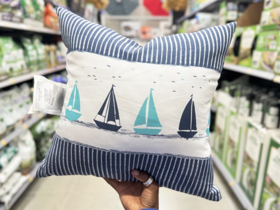 hand holding up a blue sailboat print throw pillow