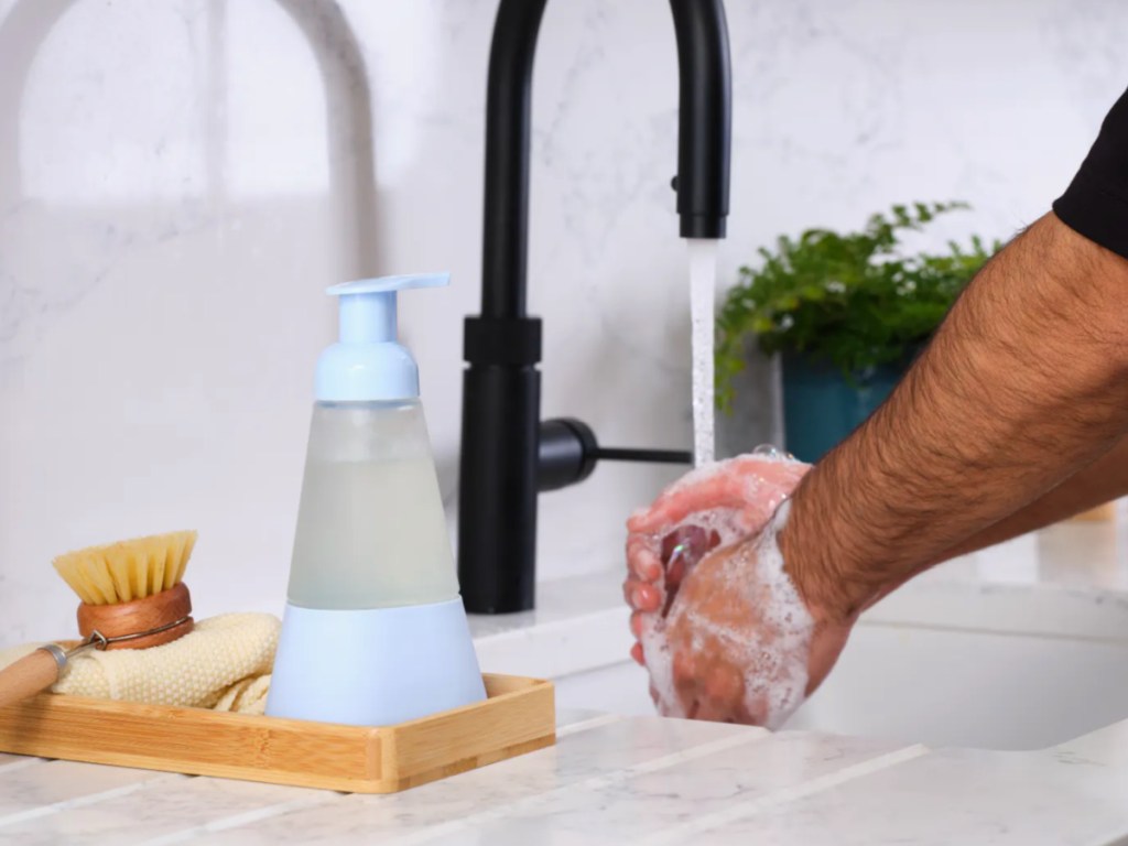 blue cleancult bottle next to man washing hands in sink