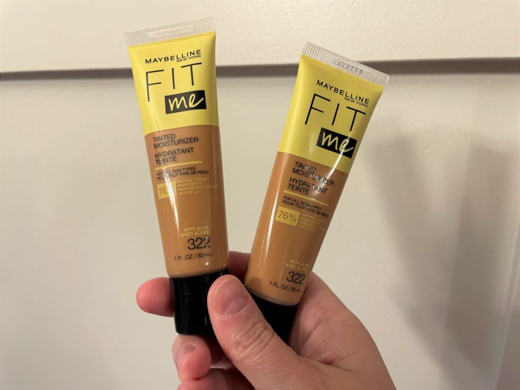 Hand holding two Maybelline Fit Me Tinted Moisturizers