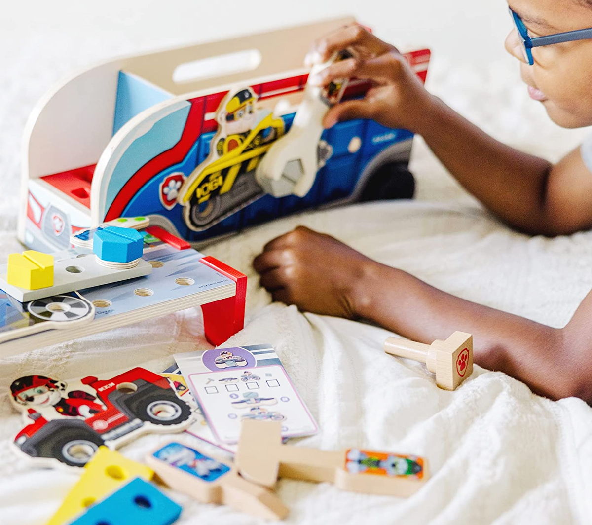 boy laying on bed playing with Melissa & Doug Paw Patrol Match & Build Mission Cruiser toy