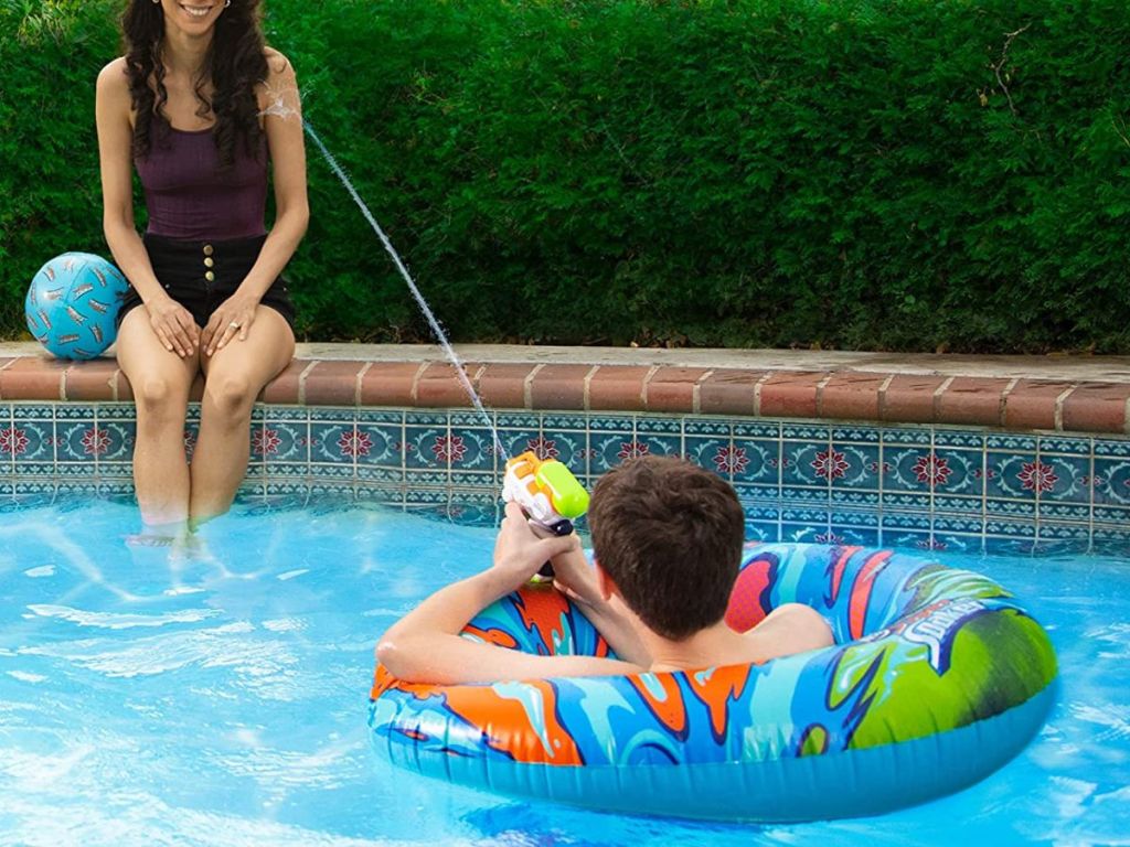 kid in a Nerf Pool Float squirting woman sitting on the side of a pool