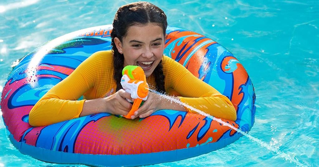 girl squirting a squirt gun in a pool float