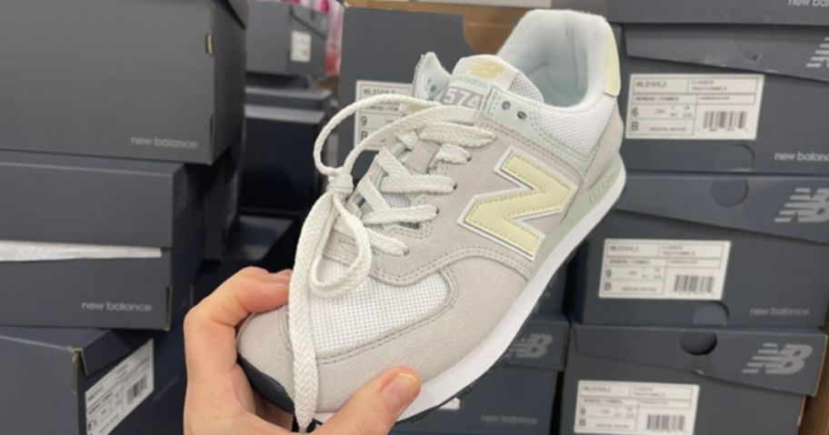 holding a pair of new balance shoes, one of the retailers that offers college student discounts in 2024