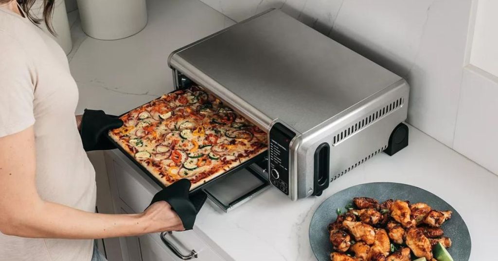Woman putting a pizza into a Ninja air fryer oven