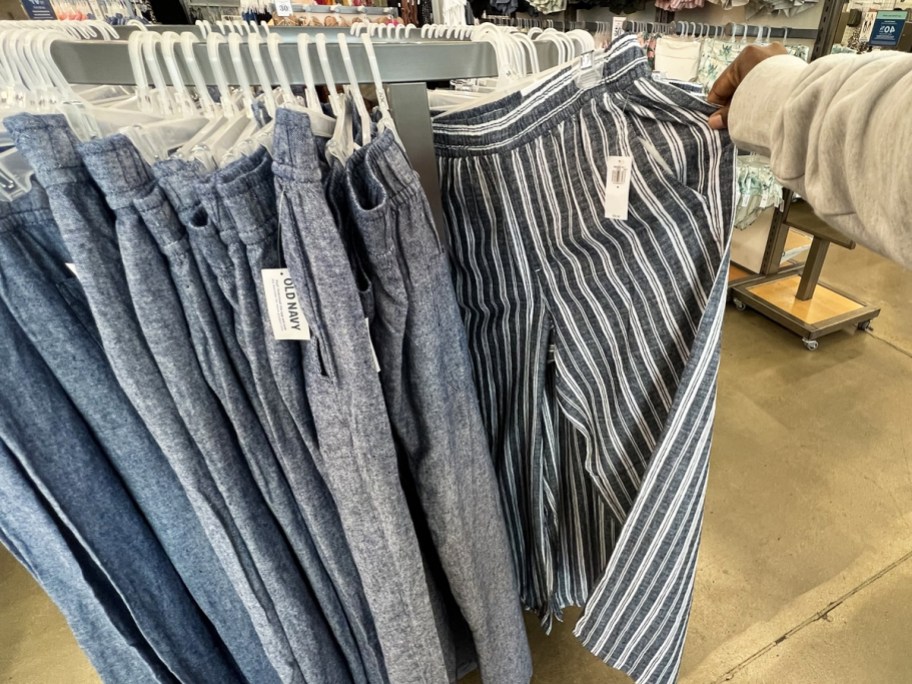 hand grabbing pair of linen pants from store display rack