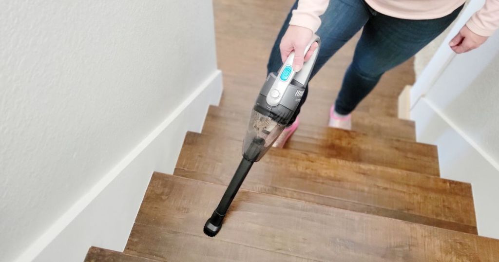 person cleaning the stairs with a handheld vacuum