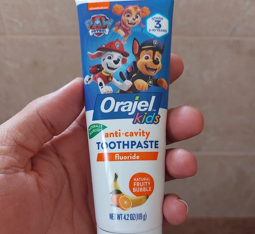 Hand holding up a tubeof Paw Patrol Orajel toothpaste for kids