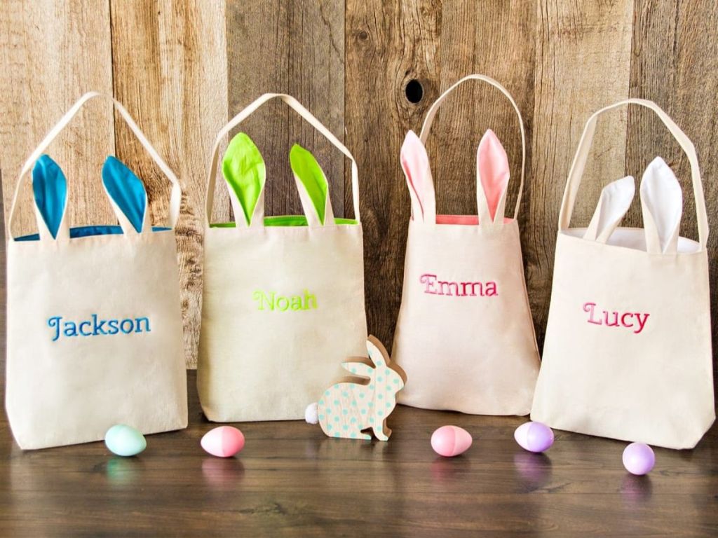 linen tote bags with bunny ears and names lined up on a table