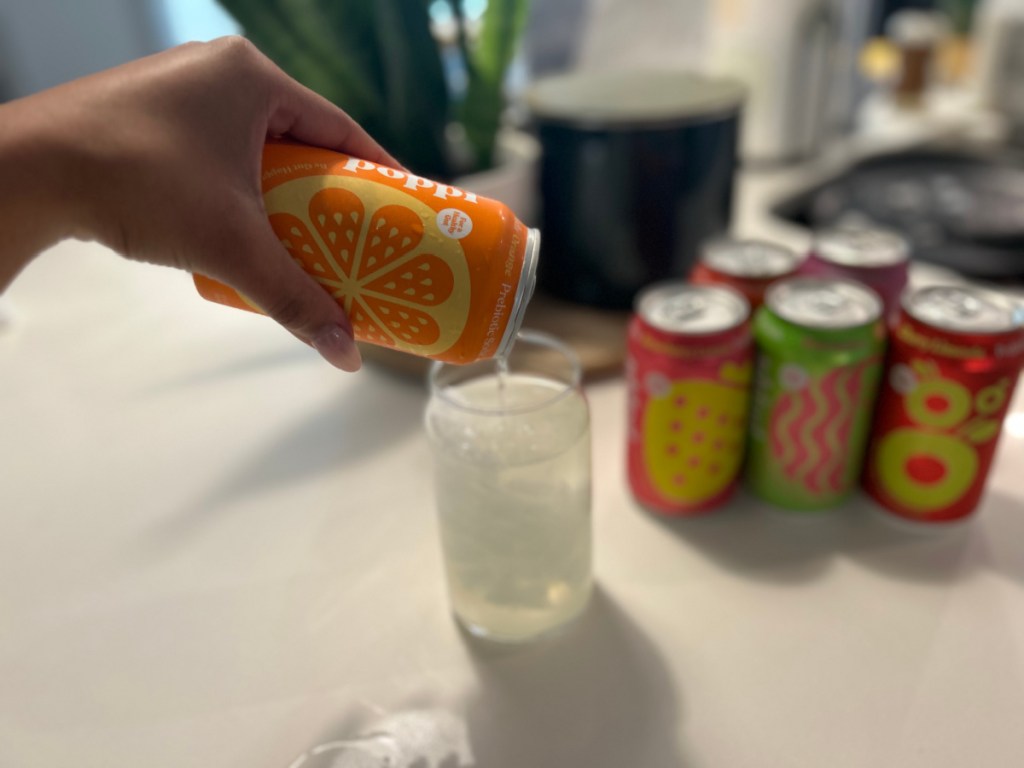 Pouring a can of poppi soda into a glass