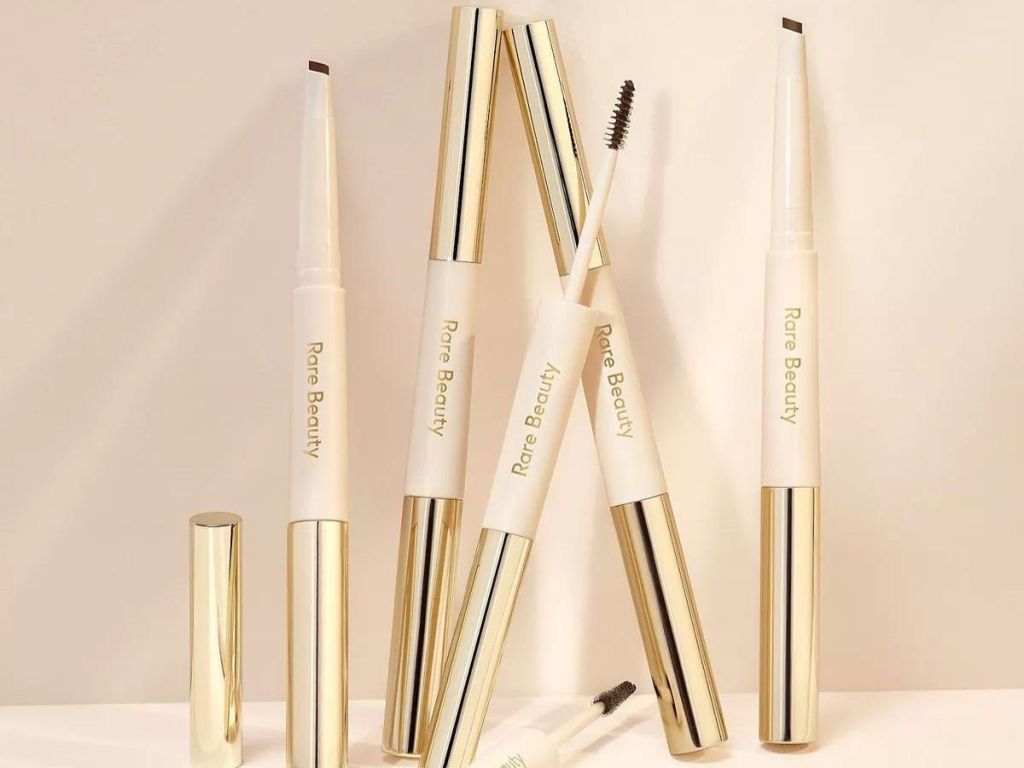 multiple Rare Beauty brow and pencil sets placed against a wall with some caps removed