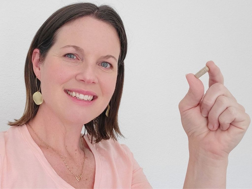woman holding up a Raw Science Perfect Skin capsule