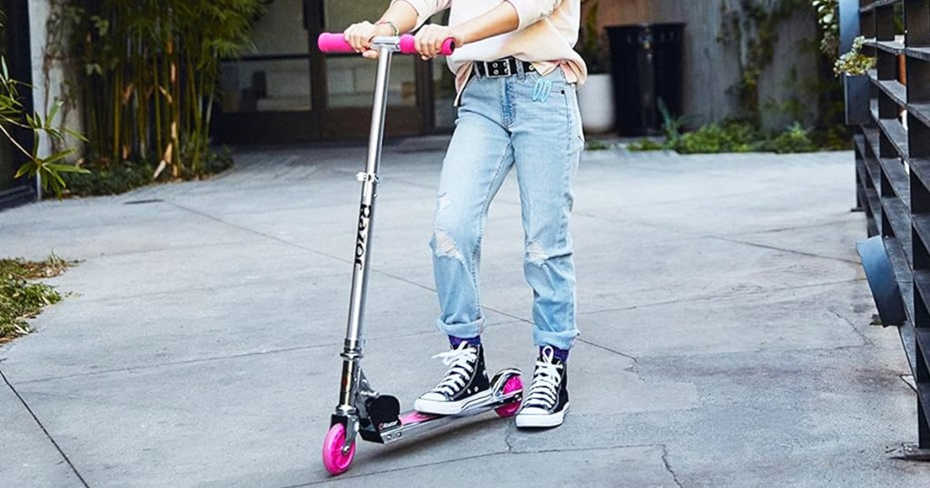 girl riding on a silver and pink razor scooter