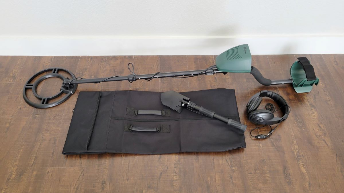 Metal detector on the floor with a bag and shovel