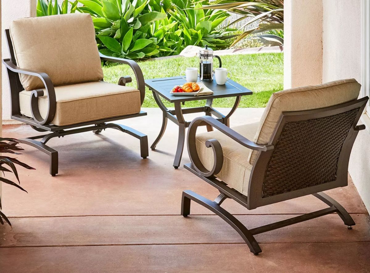 Two chairs with tan cushions on them on a patio
