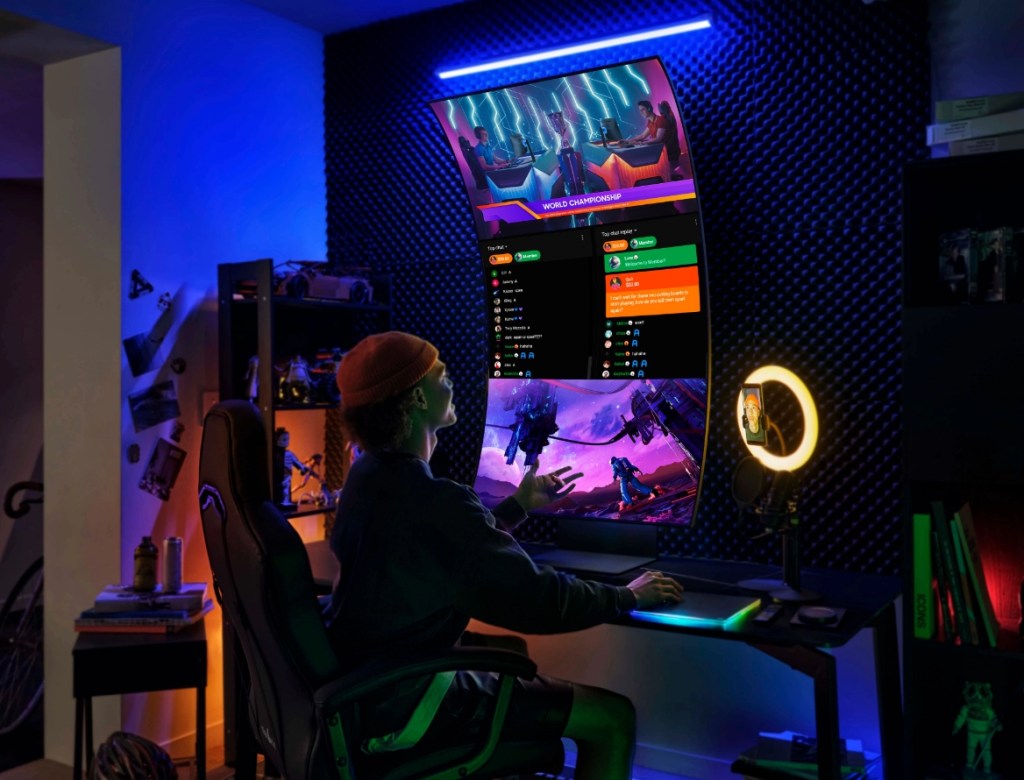 Man sitting next to a large, curved gaming screen